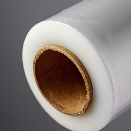 Roll of transparent polyethylene cling film on gray background close up