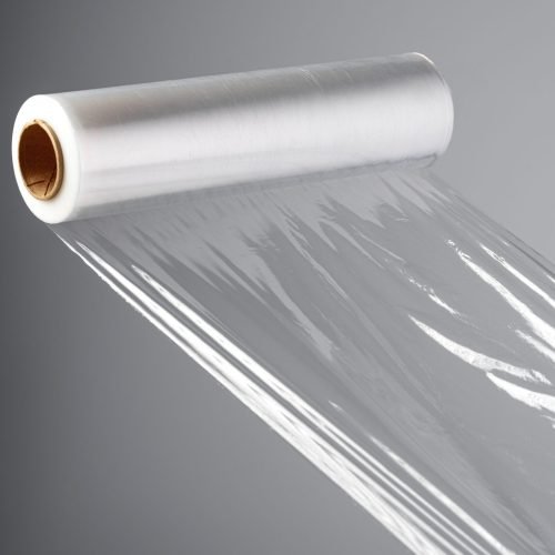 Roll of transparent polyethylene cling film on gray background close up